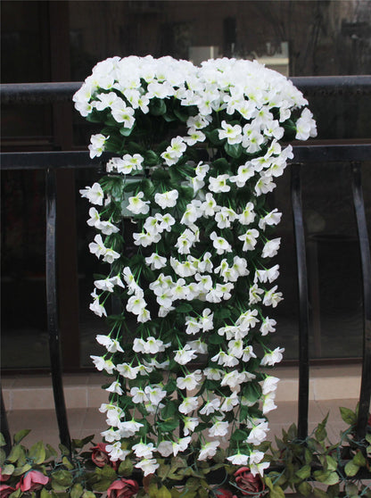 Violette Ranken hängen von künstlichen Blumen am Fensterbalkon.