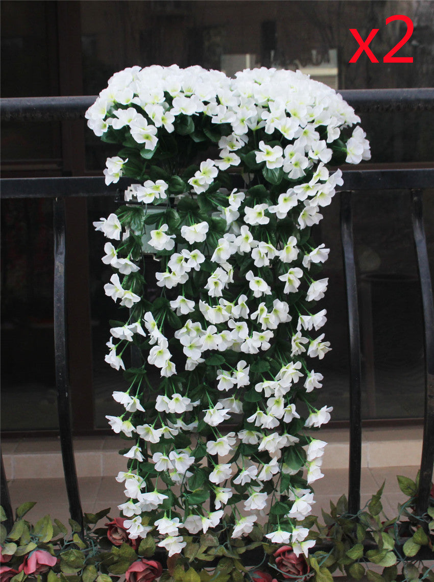 Violette Ranken hängen von künstlichen Blumen am Fensterbalkon.